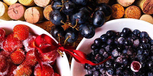 Erdbeeren, Blaubeeren und Rotweintrauben und Korkenstöpsel im Hintergrund